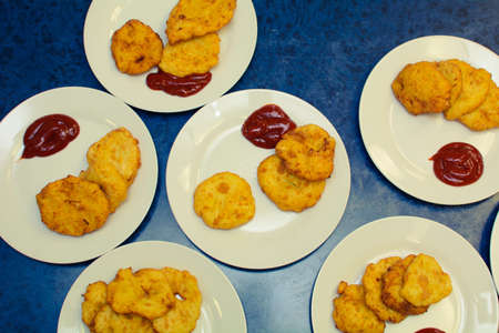 many servings of potato pancakes with ketchup on plates