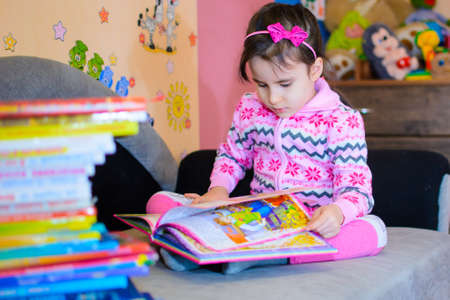 Cute girl on the background of her toys with a book