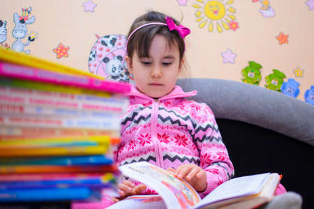 Cute girl on the background of her toys with a book
