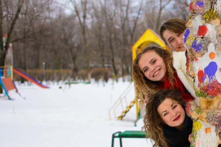 three friends are posing in winter at a tree