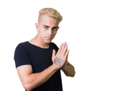 handsome trendy young guy in a black shirt on a white background. folded his arms as he prays.の写真素材