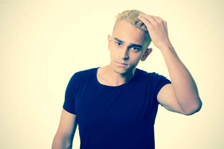 handsome trendy pensive young guy straightens her hairの写真素材