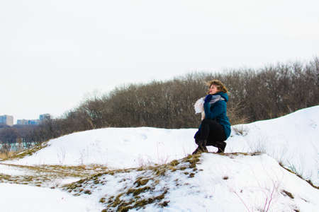 girl in winter sits on a hill. concept of thoughtfulness or sadnessの写真素材
