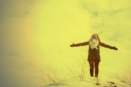 girl in winter stands on a hill with his hands up. concept of freedom or victory