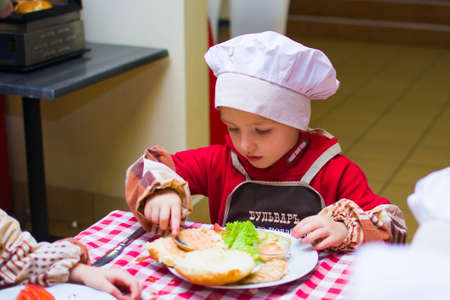 Alchevsk, Ukraine - November 7, 2018: children in the form of cooks prepare burgers.のeditorial素材