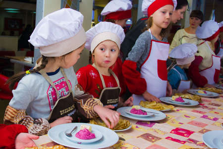 Alchevsk, Ukraine - November 21, 2018: children in the form of cooks prepare pancakes.のeditorial素材