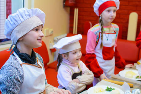 Alchevsk, Ukraine - April 6, 2018: children in the form of cooks prepare pizza horn.のeditorial素材