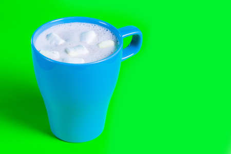 cocoa with marshmallows in a blue mug on a green background.の写真素材