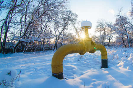 An old yellow gas pipe with a crane in a winter park sticks out from under the ground. Blocked the gasの写真素材