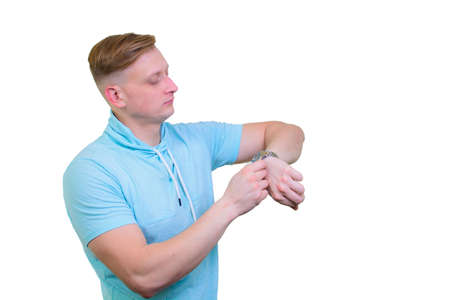 Portrait of a cheerful young guy turning on a wristwatch.