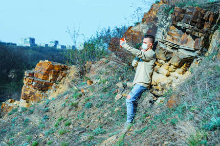 medical mask as protection against coronavirus. guy in the mountains isolated from coronavirus. makes selfieの写真素材