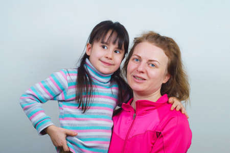 a mother with blond hair and her daughter are smiling and hugging.の写真素材