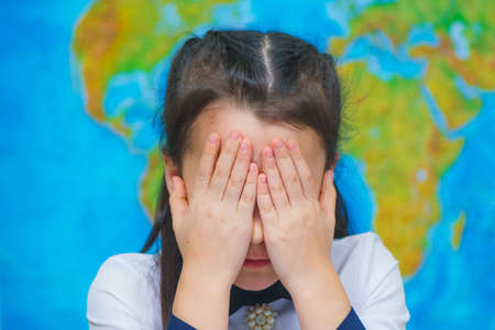 Close-up portrait of smart cute girl on the background of the world map.