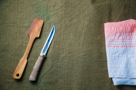 The wooden spatula and knife lie on a green ragcloth next to the napkin. Serving for the dishの写真素材