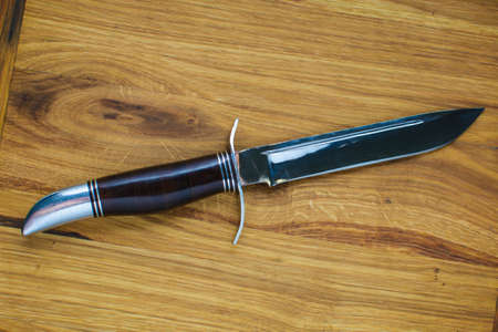 a beautiful mirror knife for hunting lies on a wooden cutting board. handwork