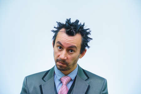 Shocked businessman with tousled hair looks into the camera.の写真素材