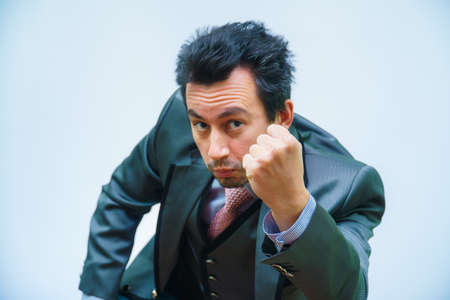 businessman with tousled hair looks at the camera shaking his fist