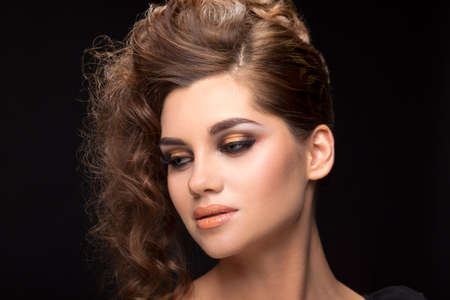 Portrait of a young brunette woman hairstyle curls on a black background.の写真素材