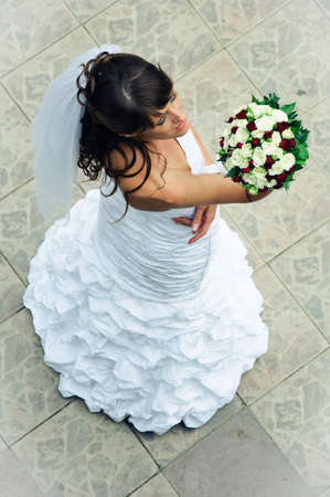 beautiful bride in a white dress look to wedding bouquetの写真素材