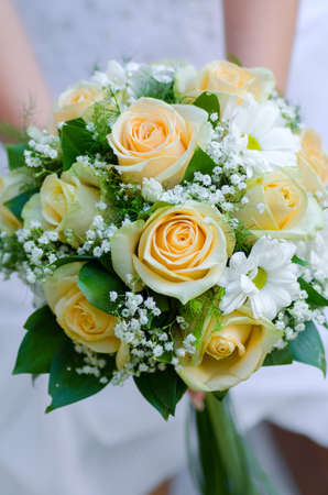 bride holding beauty wedding bouquet of yellow roses and white camomileの写真素材