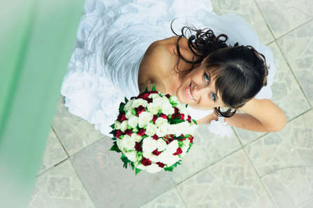 smiling bride with bunch of flowers to upward lookingの写真素材