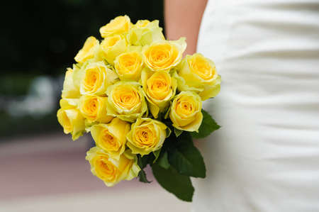 Wedding bouquet with many yellow roses in hands of brideの写真素材