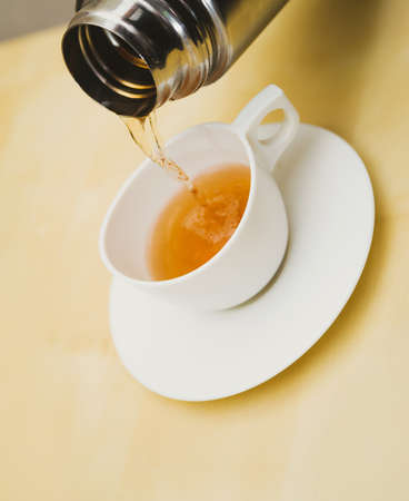 pour a white cup of tea. focus on a bottom of capの写真素材