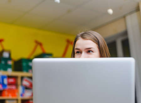 cheerful business young woman looking from behind laptopの写真素材