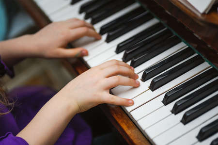 kids hands on a white piano key. Playing musicの写真素材