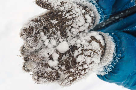 kid showing winter gloves with a snowの写真素材