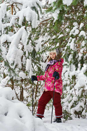 kid skiing stands in the winter snowy forestの写真素材