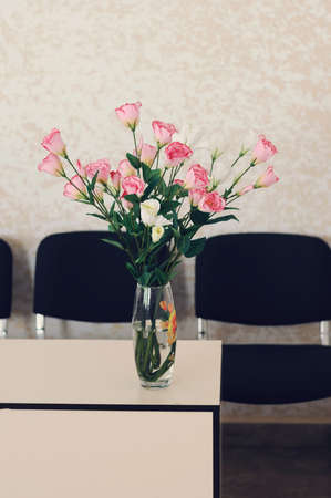 many beautiful roses standing in a vase in the office. Beauty in a boring officeの写真素材