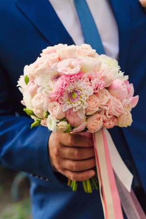 wedding bouquet of the bride in the hands of the groomの写真素材
