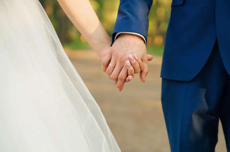 wedding couple, bride and groom holding hands. Hands close upの写真素材