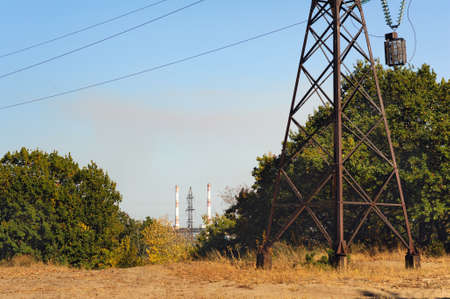 Electricity tower in autumn forest. View on the factory pipes. Smog in the air. This is environmental problemの写真素材