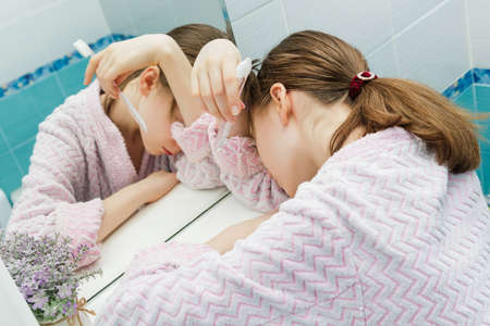 sleeping teen girl with a toothbrush in her hands in the bathroomの写真素材