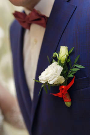 white rose on a groom blue coat. Close-up photo. Selective focus on white flowerの写真素材