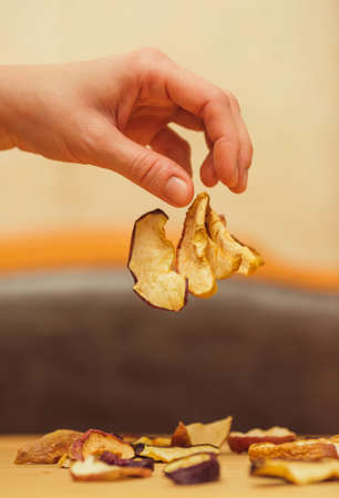 Pieces of dried fruit fall on the table from the unclenched hand. Dried apples are an ingredient for compote. Selective focusの写真素材