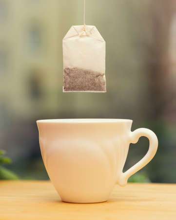 dry new disposable tea bag hanging over a white mug. Selective focus on tea bagの写真素材