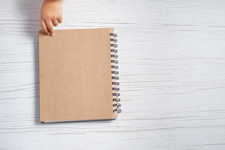 Notepad and childs hand on a white tableの写真素材