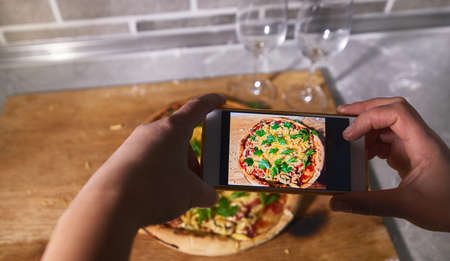 The process of photographing a cooked pizza on a smartphoneの写真素材