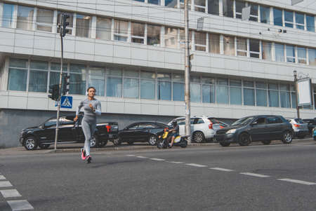 A young woman running on a crosswalkの写真素材