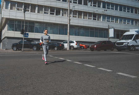 A young woman running on a crosswalkの写真素材