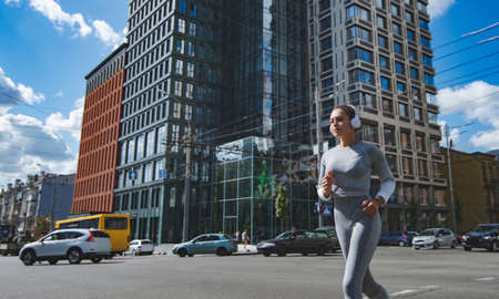 The athlete runs in the city next to passing carsの写真素材