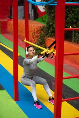 The young woman squatting with yellow athletic strapsの写真素材