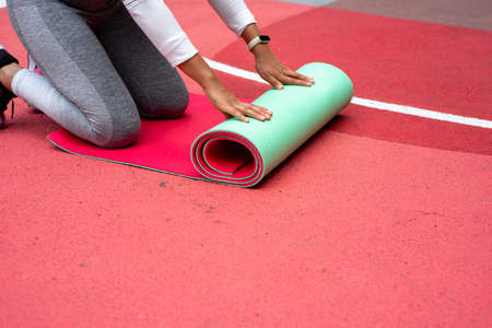 The young woman spreads green mat over red surface with handsの写真素材