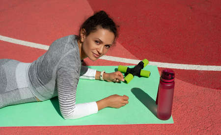 The young woman in a gray tracksuit lies on her stomach looking at usの写真素材