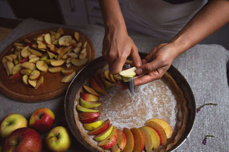 Preparation, Thanksgiving Day celebration. A cook cuts the apples into pieces on a baking sheet with a pie. View from above. Making a traditional apple pie.の写真素材