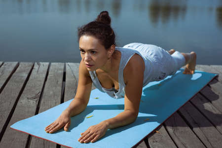 The young woman doing plank exercise on a gymnastic mat. Meditation, yoga in nature.