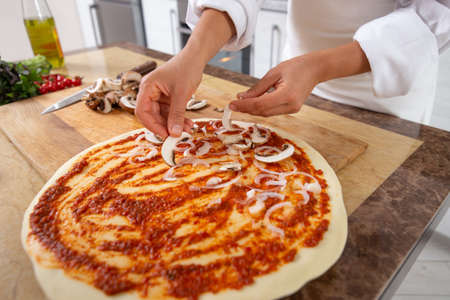 Close-up on the hands of cook laying mushrooms on a pizza. Vegan food.の写真素材